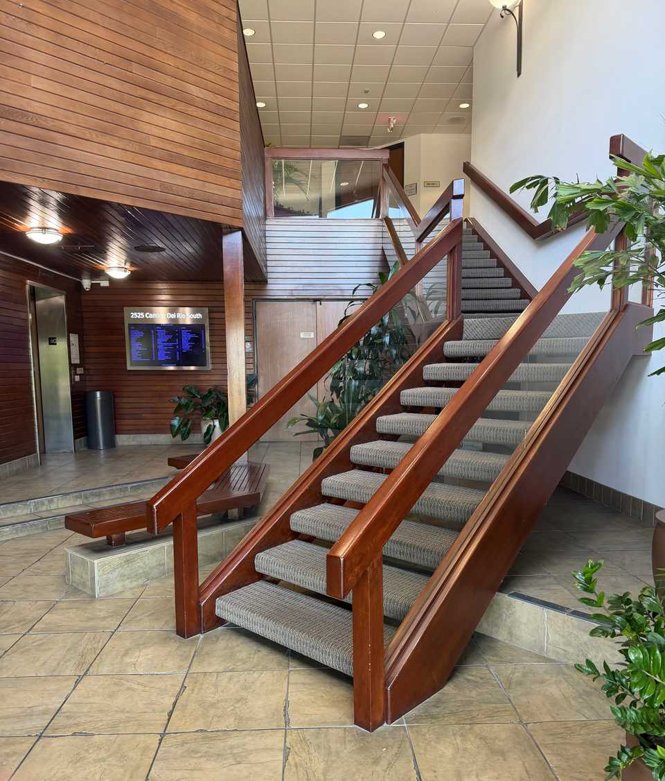 Building lobby with the elevator on the left and a wooden staircase to the second floor