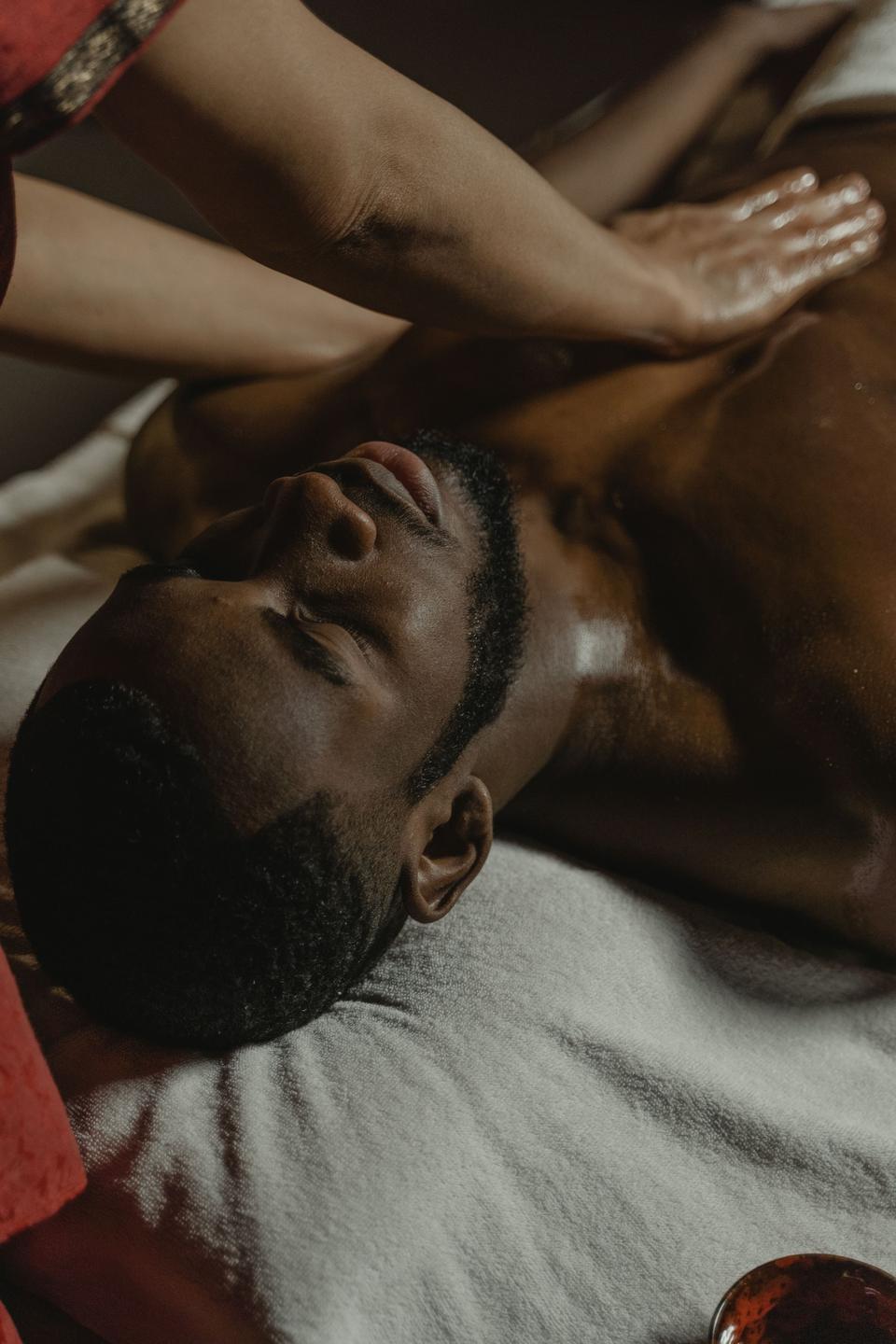 A man resting with his eyes closed as hands massage his shoulder