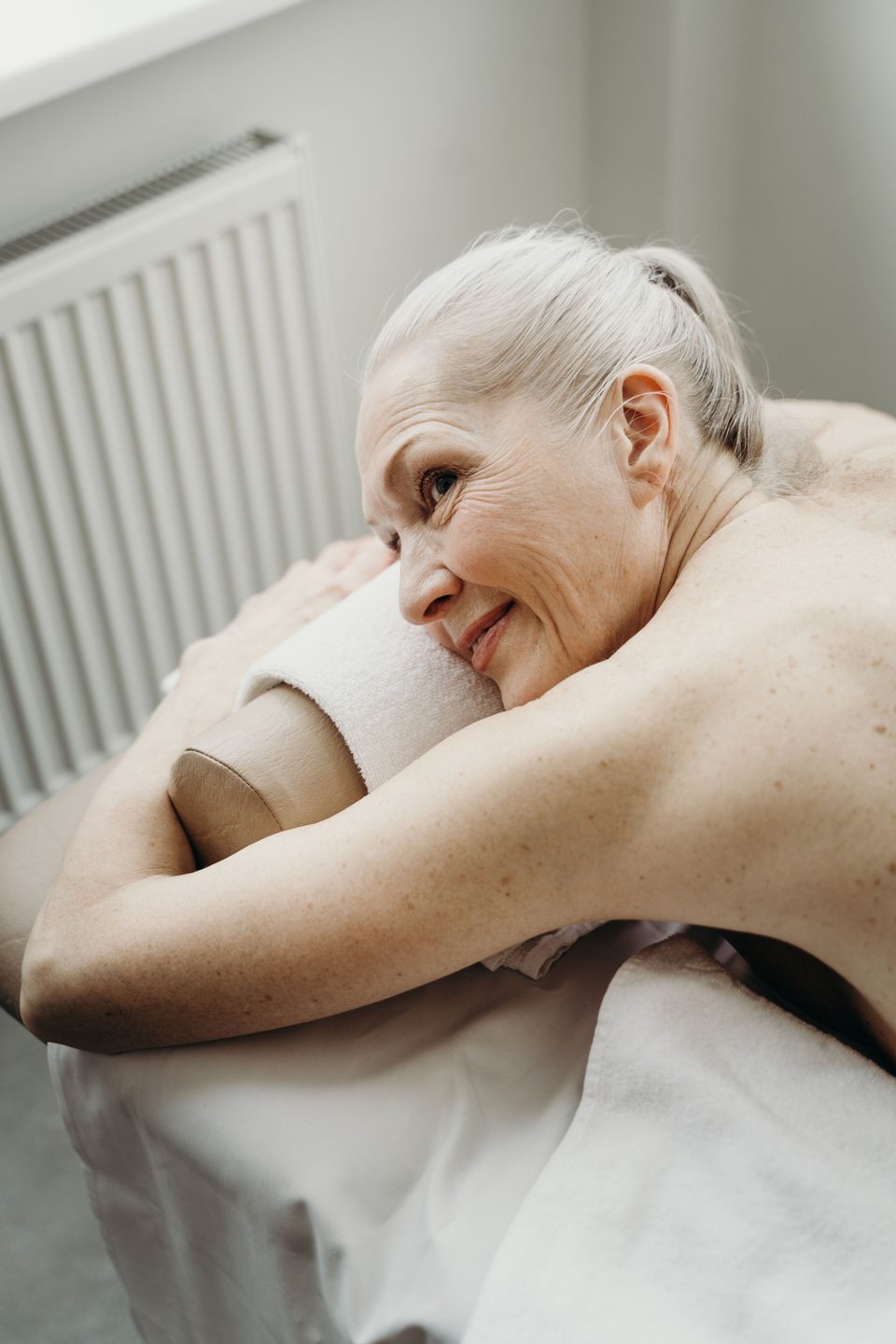 An older woman smiling as she relaxes on a massage table
