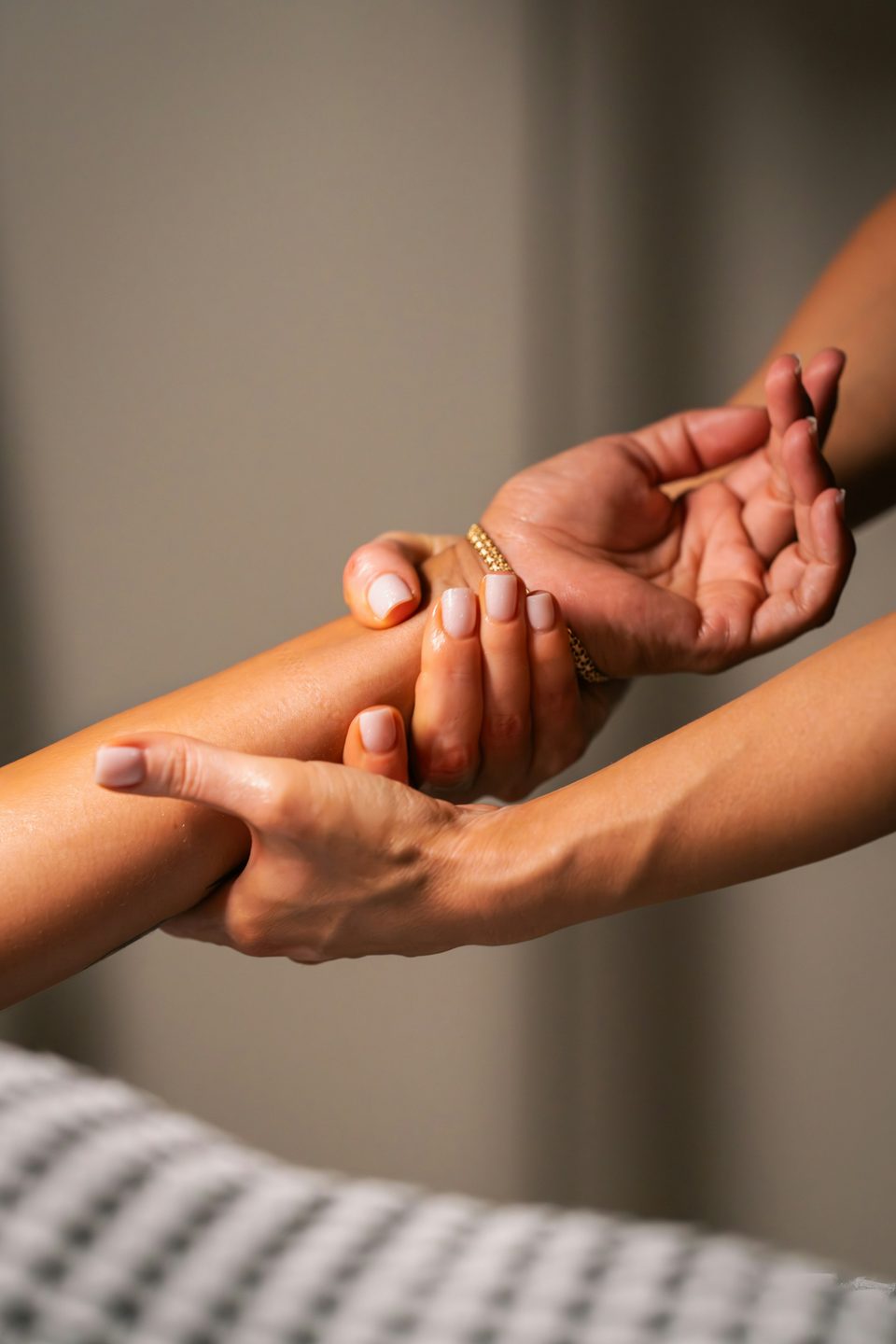 Hands applying gentle pressure along a person&rsquo;s forearm